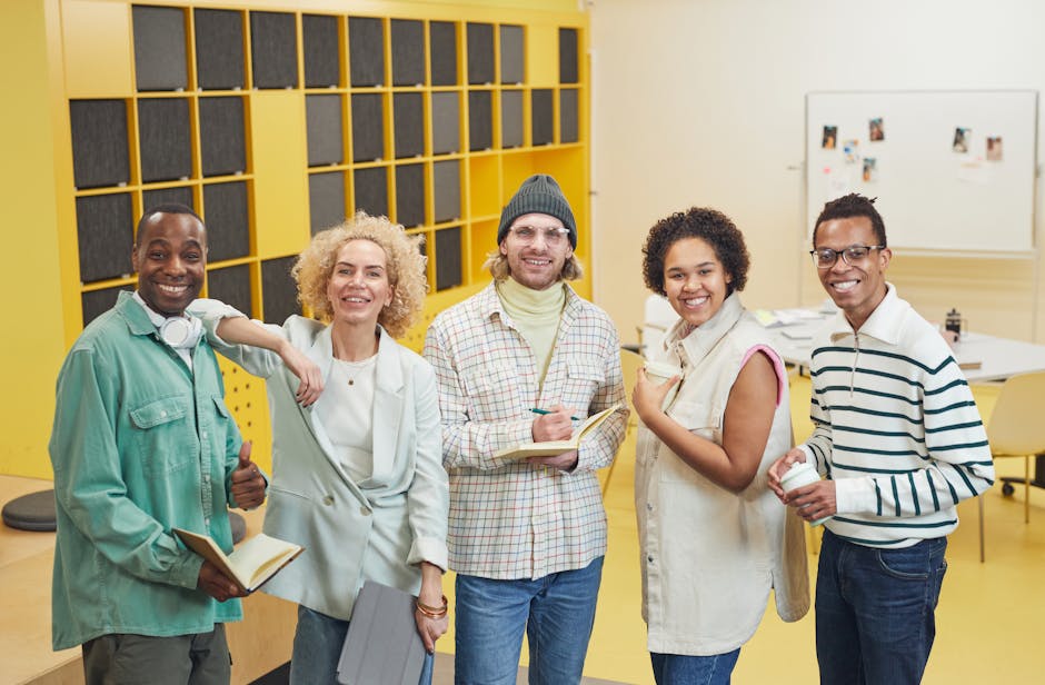 A cheerful diverse team in a modern office, posing together with notebooks and smiling at the camera.